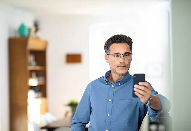 Mann liest sein Handy mit Lesebrille